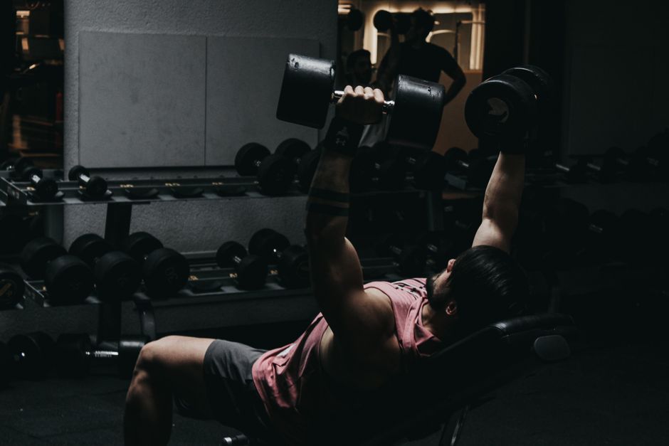 Muscular man u teretani izvodi bench press s bučicama