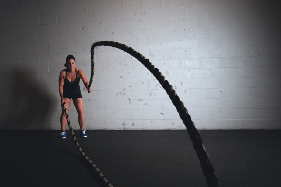 Žena izvodi vježbu s battle rope u teretani
